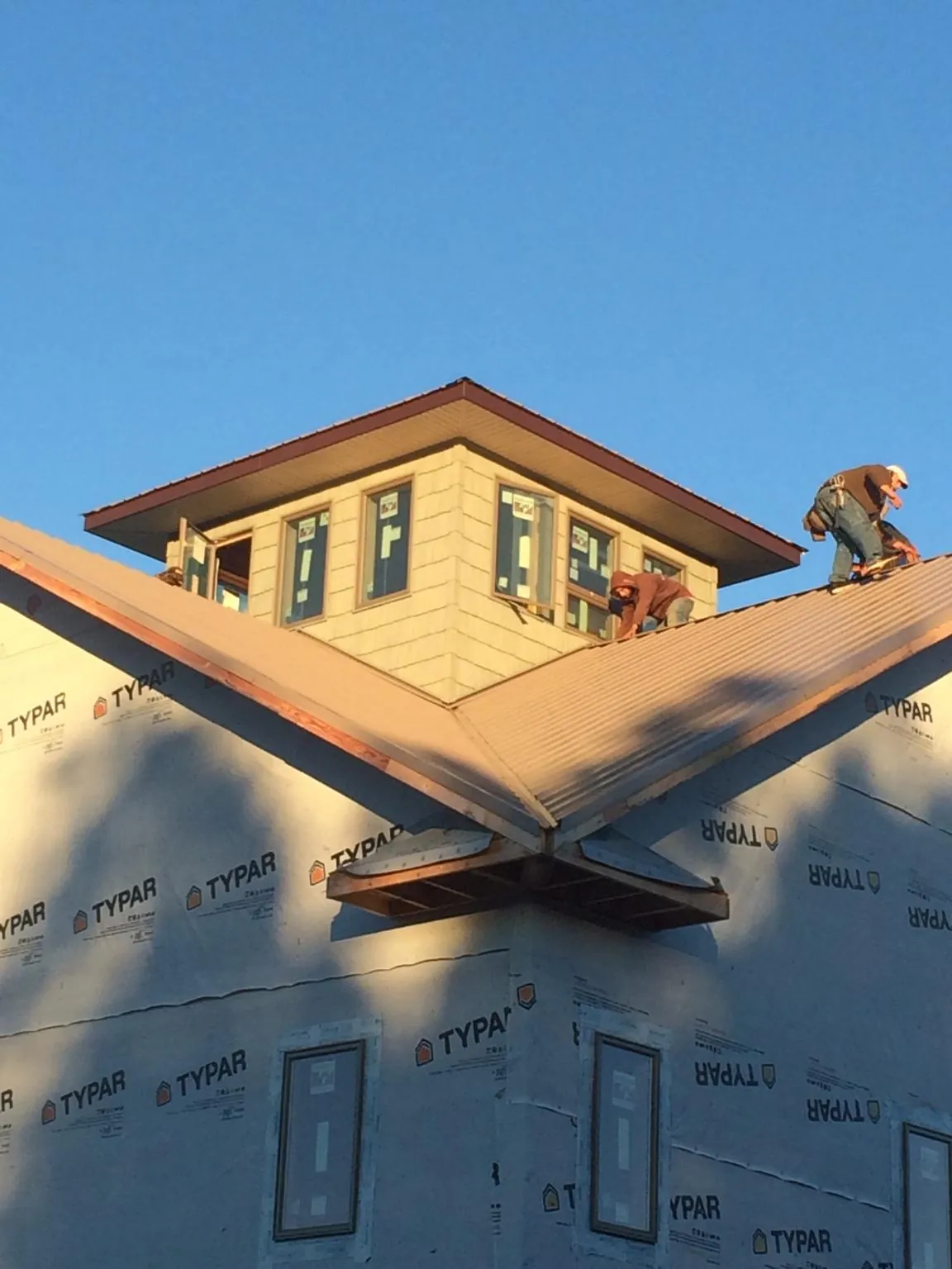 Roofers working around a rooftop cupola on a new metal roof at sunset — Roof Waterproofing in Adams by Roofing Brothers
